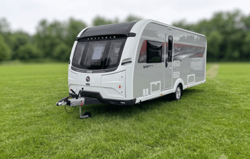 Coachman caravan that is on grasswith trees surrounding the field