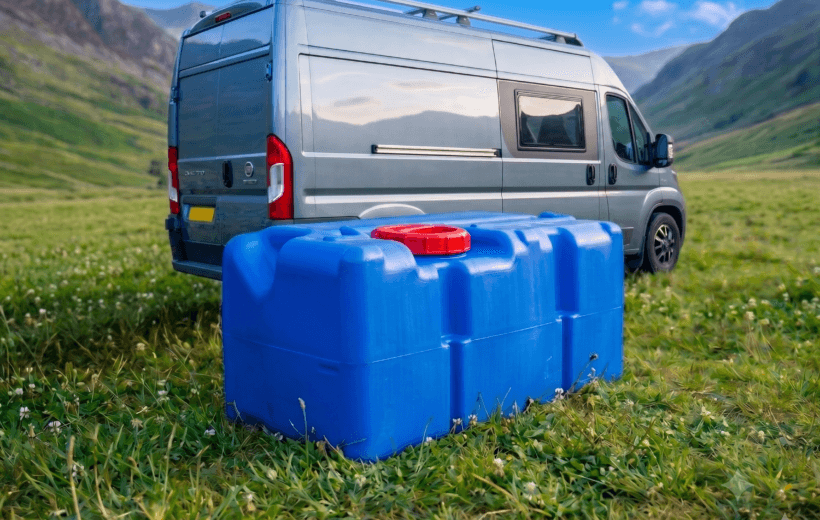 Slate grey Fiat Ducato motorhome with a fresh water tank outside of it on the grass