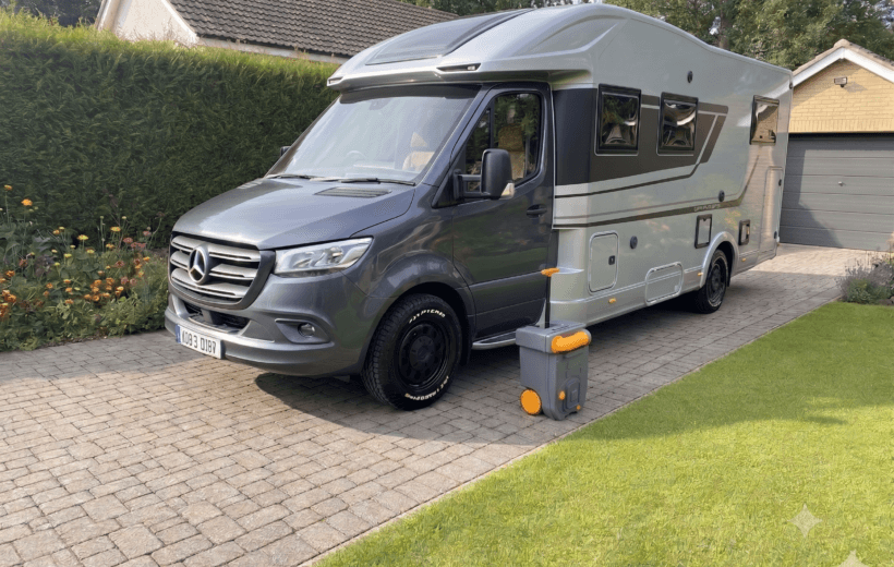 Mercades based motorhome with a toilet cassette next to it on it's drive